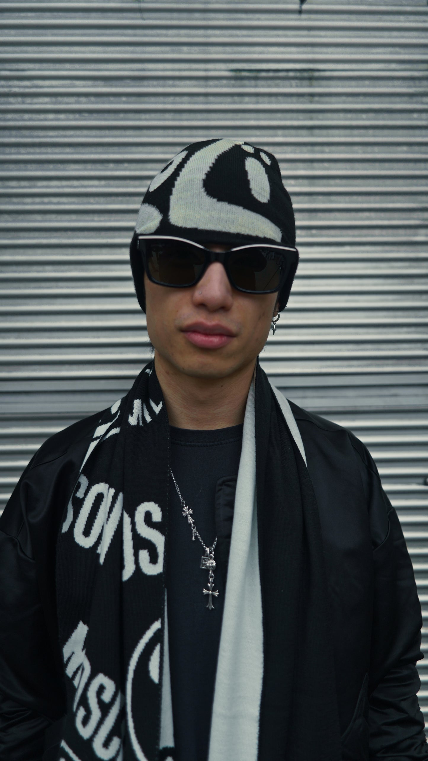 Person wearing a black and white patterned knit hat with the text "KOZI" against a metallic background